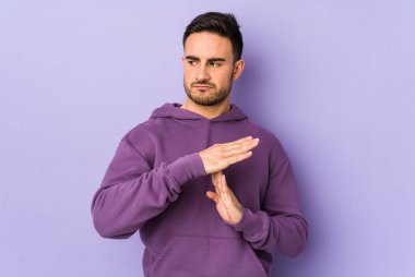 Mor arka planda izole edilmiş genç beyaz bir adam bir mola hareketi gösteriyor..