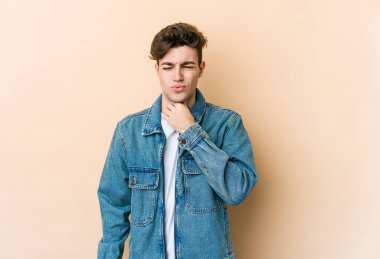 Beyazlı genç bir adam bej arka planda virüsten ya da enfeksiyondan boğaz ağrısı çekiyor..