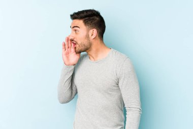 Mavi arka planda izole edilmiş genç beyaz bir adam gizli bir sıcak fren haberi veriyor ve yana bakıyor.