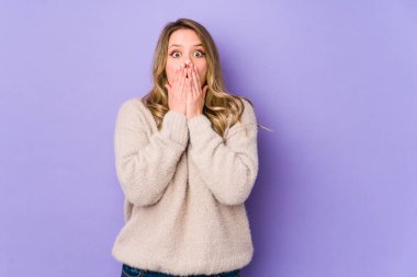 Mor arka planda izole edilmiş beyaz bir kadın elleriyle ağzını kapatırken şok oldu..