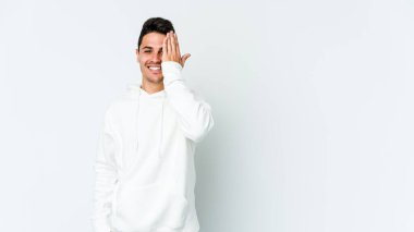 Beyaz arka planda izole edilmiş genç beyaz bir adam yüzünün yarısını palmiye ile örterek eğleniyor..