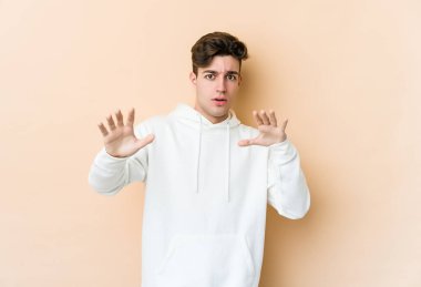 Beyazlı genç bir adam bej arka planda izole edildi. Yakın bir tehlike nedeniyle şoka girdi.