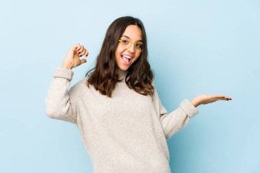 Genç, melez, İspanyol bir kadın avucunun içinde fotokopi alanı tutuyor, el üstünde tutuyor. Şaşırmış ve mutlu..