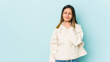 Mavi arka planda izole edilmiş genç bir kadın virüs veya enfeksiyon nedeniyle boğaz ağrısı çekiyor..