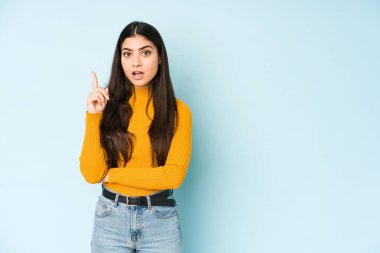 Genç Hintli bir kadın mavi arka planda izole edilmiş. Harika bir fikri var. Yaratıcılık kavramı..