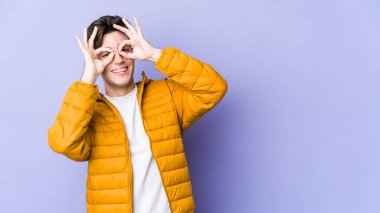 Mor arka planda izole edilmiş genç beyaz adam gözlerinde sorun olmadığını gösteriyor.