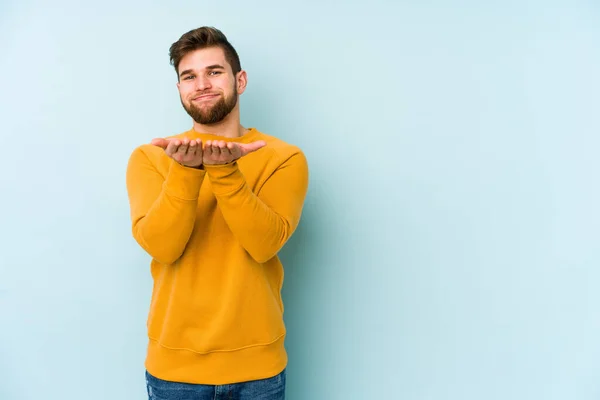 Ung Kaukasisk Man Isolerad Blå Bakgrund Håller Något Med Handflator — Stockfoto