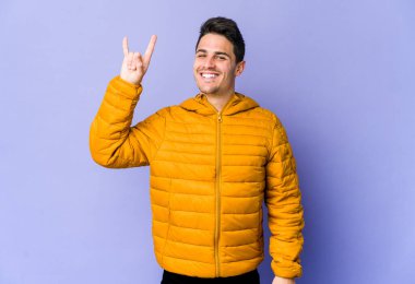 Mor arka planda izole edilmiş genç beyaz adam boynuzlarını devrim konsepti olarak gösteriyor..