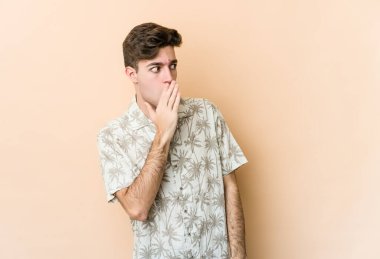 Beyazlı genç bir adam bej arka planda izole edilmiş. Gördüğü bir şey yüzünden şok oluyor..