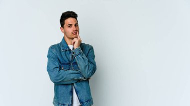 Beyaz arka planda izole edilmiş genç beyaz adam alaycı bir ifadeyle kameraya bakıyor..