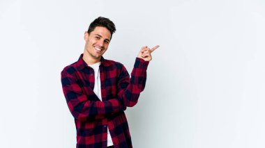 Beyaz arka planda izole edilmiş genç beyaz adam işaret parmağıyla işaret ederek gülümsüyor..