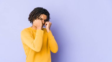 Rasta saç stili giymiş genç siyah bir adam bir tartışma yüzünden yumruk atıyor, sinirleniyor, kavga ediyor, boks yapıyor.