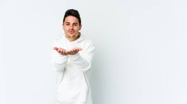Beyaz arka planda izole edilmiş genç beyaz bir adam dudaklarını katlıyor ve hava öpücüğü vermek için avuç içleri tutuyor..