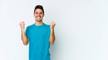 Beyaz arka planda izole edilmiş genç beyaz adam tasasız ve heyecanlı bir şekilde tezahürat yapıyor. Zafer konsepti.