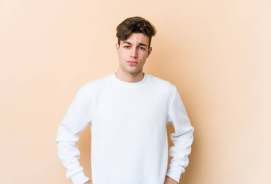 Beyazlı genç bir adam bej arka planda izole edilmiş üzgün, ciddi yüzlü, mutsuz ve hoşnutsuz..