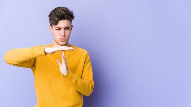 Mor arka planda izole edilmiş genç beyaz bir adam bir mola hareketi gösteriyor..