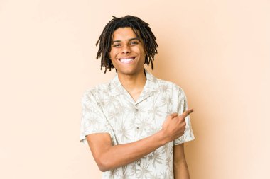 Genç Afrikalı Amerikalı Rasta adam gülümsüyor ve boş alanda bir şey gösteriyor..