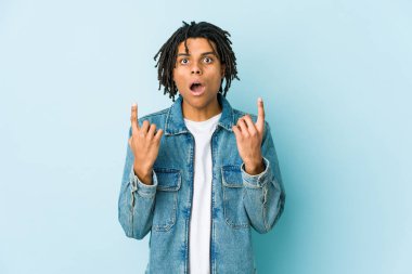 Kot ceketli genç bir adam ağzı açık, üst tarafı işaret ediyor..