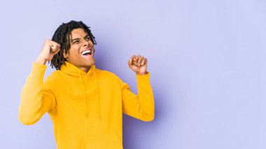 Genç Afrikalı Amerikalı Rasta adam zafer ve galibiyet kavramından sonra yumruğunu kaldırıyor..