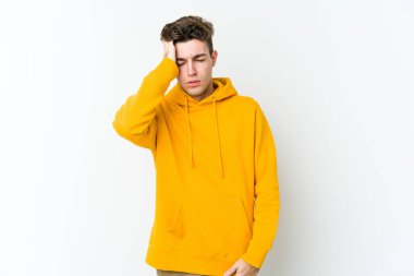 Beyaz arka planda izole edilmiş genç beyaz bir adam yorgun ve uykulu bir şekilde elini başının üstünde tutuyor..