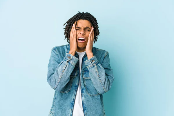 Young black man wearing a jeans jacket whining and crying disconsolately.