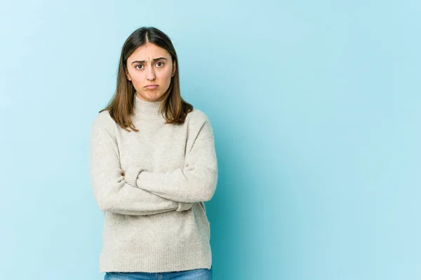 Young caucasian woman blows cheeks, has tired expression. Facial expression concept.