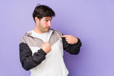 Mor arka planda izole edilmiş genç adam parmağını göstererek şaşırdı, geniş bir gülümsemeyle..