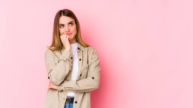Pembe arka planda izole edilmiş genç beyaz kadın rahatça fotokopi odasına bakan bir şey düşünüyor..