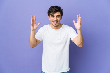 Hoş bir sürpriz yapan genç havalı adam heyecanlı ve el kaldırıyor..