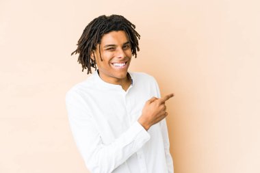 Genç Afrikalı Amerikalı Rasta adam gülümsüyor ve boş alanda bir şey gösteriyor..