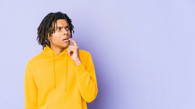 Genç Afrikalı Amerikalı Rasta adam şüpheli ve şüpheci bir ifadeyle yana bakıyor..