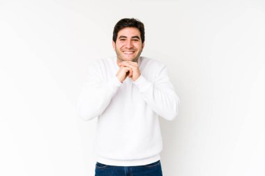 Beyaz arka planda izole genç adam ellerini çenesinin altında tutuyor, mutlu bir şekilde yan tarafa bakıyor..