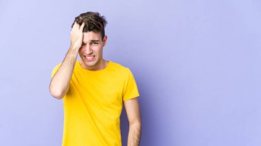 Mor arka planda izole olmuş genç beyaz bir adam bir şeyi unutuyor. Alnına avuç içi ve gözlerini kapayarak vuruyor..