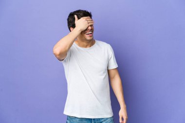 Genç, havalı adam elleriyle gözlerini kapatıyor, gülümseyerek bir sürpriz bekliyor..