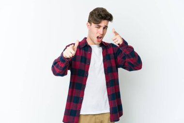 Beyaz arka planda izole edilmiş genç beyaz adam parmaklarıyla ön tarafı işaret ediyor..