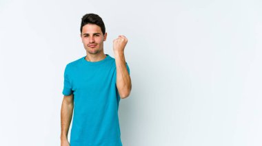 Beyaz arka planda izole edilmiş genç beyaz bir adam yumruğunu kameraya gösteriyor, agresif bir yüz ifadesi..