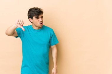 Genç havalı adam baş parmağını aşağı gösteriyor ve hoşlanmadığını ifade ediyor..