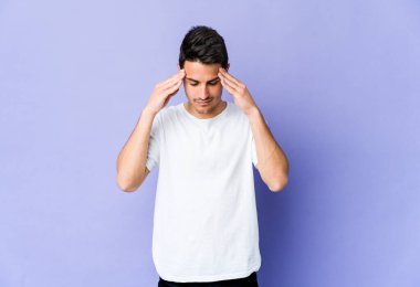 Mor arka planda izole edilmiş genç beyaz adam tapınaklara dokunuyor ve baş ağrısı çekiyor..