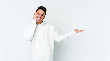 Beyaz arka planda izole edilmiş genç beyaz bir adam bir avuç içinde fotokopi alanı tutuyor, el üstünde tutuyor. Şaşırmış ve mutlu..