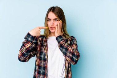 Mavi arka planda izole genç beyaz kadın güçlü bir diş ağrısı, azıdişi ağrısı var..