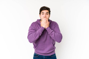 Beyaz arka planda izole edilmiş genç adam elleriyle ağzını kapatırken şok oldu..