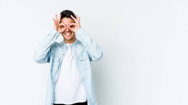 Beyaz arka planda izole genç beyaz adam heyecanlı tamam göz jesti tutmak.