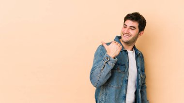 Bej arka planda izole edilmiş genç bir adam başparmak uzakta, gülüyor ve kaygısız..