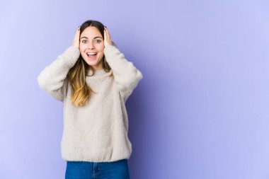 Mor arka planda izole edilmiş genç beyaz bir kadın çığlık atıyor, çok heyecanlı, tutkulu, bir şeyden memnun..