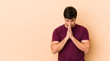 Bej arka planda izole edilmiş genç bir adam dua ediyor, bağlılık gösteriyor, dindar biri ilahi ilham arıyor..