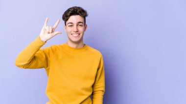 Mor arka planda izole edilmiş genç beyaz adam boynuzlarını devrim konsepti olarak gösteriyor..