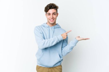 Beyaz arka planda izole edilmiş genç beyaz bir adam, palmiye üzerinde bir fotokopi alanı tutarken heyecanlı..