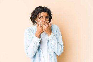 Genç Afro-Amerikan Rasta adam elleri ve ağzı kapalı endişeli görünüyor..