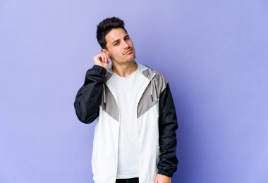 Genç beyaz adam mor arka planda izole edilmiş parmaklarıyla kulaklarını kapatıyor, gürültülü bir ortam tarafından stresli ve umutsuz..