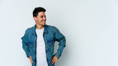 Beyaz arka planda izole genç beyaz adam mutlu bir şekilde gülüyor ve ellerini karnının üstünde tutarak eğleniyor..